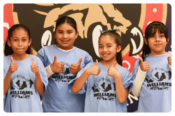 Four students giving a thumbs up, wearing blue shirts with the word Williams on the front.